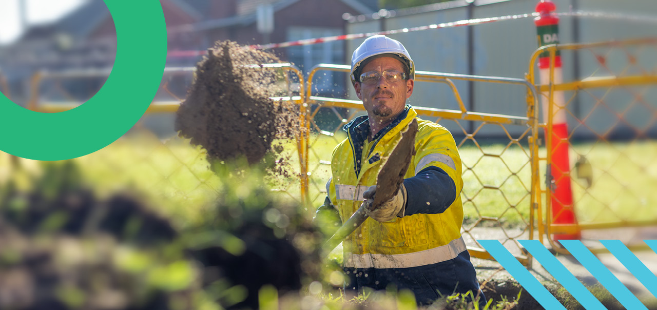 man shoveling dirt at gas works zone