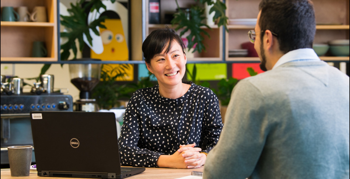 A woman and a man talking at a desk