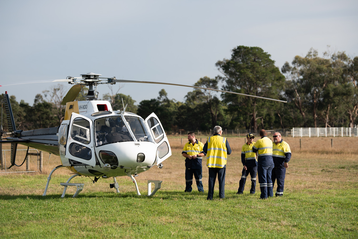 A group of workers outside standing next to a helicopter